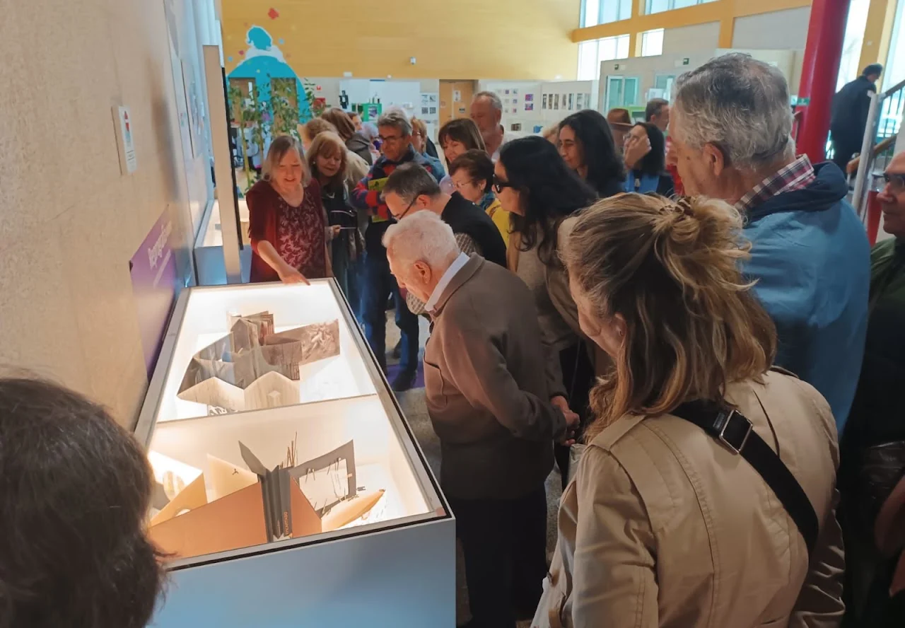 Alumnado del CEPA observa los libros de artista expuestos en vitrinas de la biblioteca.